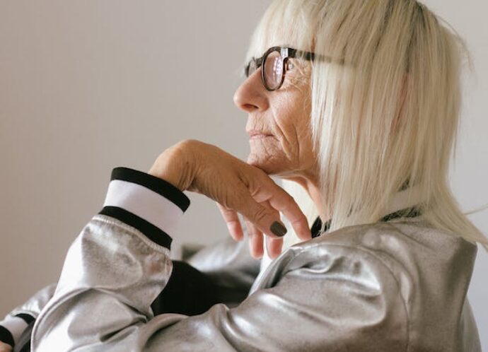 Starsza kobieta w blond włosach i okularach siedzi